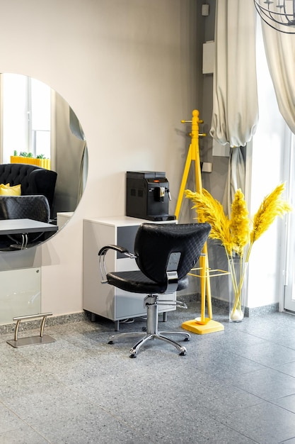 Moderner kleiner heller Friseur- und Schönheitssalon in schwarzen und gelben Farben mit grauen Wänden und Boden