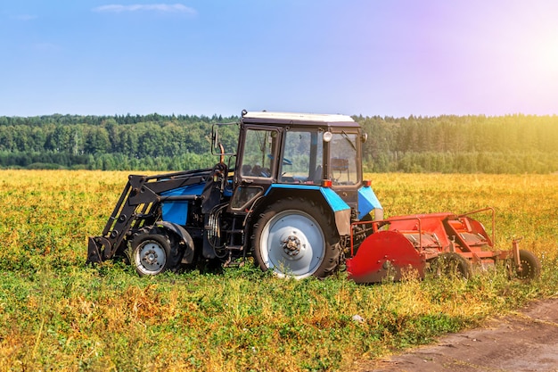 Moderner landwirtschaftlicher Radtraktor mit Ernteausrüstung auf einem Feld