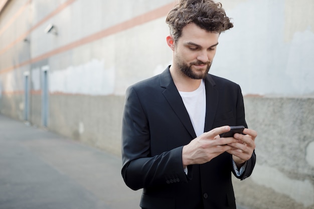 moderner Mann des hübschen Hippies, der intelligentes Telefon verwendet