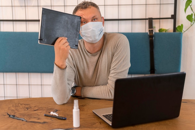 Moderner Mann mit der medizinischen Maske, die ein Notizbuch hält