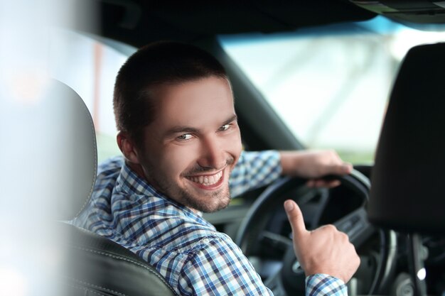 Foto moderner mann sitzt in einem auto und zeigt seinen daumen nach oben