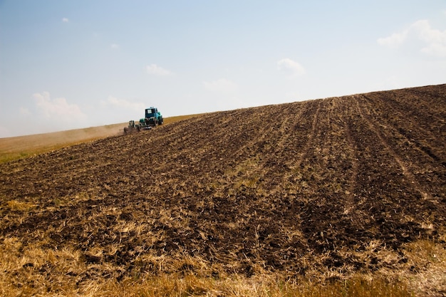 Moderner Traktor im Feld mit Komplex für das Pflügen Das Konzept der Arbeit in einer Feld- und Landwirtschaftsindustrie