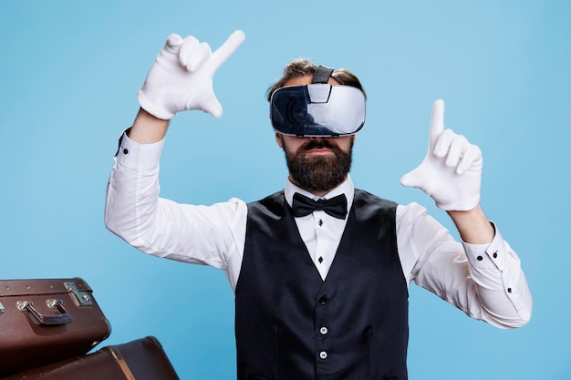 Moderner Türsteher nutzt VR-Headset vor blauem Hintergrund und genießt ein interaktives 3D-Vision-Erlebnis. Professioneller Pagen-Hotelangestellter, der Spaß mit einer Virtual-Reality-Brille hat.