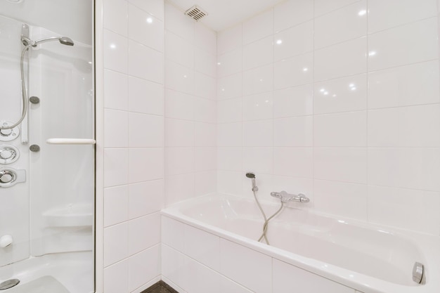 Modernes Badezimmer mit Badewanne und Glasduschkabine mit hellweißen Fliesen und dunkler Decke