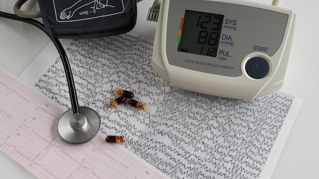 Modernes elektrisches Tonometer und ein Stethoskop auf einem Kardiogrammdiagramm. Blutdruckmessgerät für den Haushalt