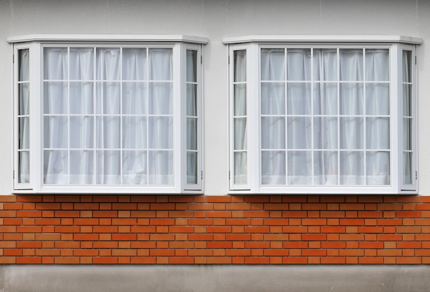 Modernes Glasfenster mit Ziegelsteinblock auf Zementfassadenwandhintergrund.