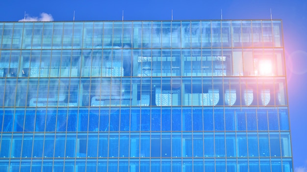 Modernes Glasgebäude mit blauem Himmelshintergrund. Ansicht und Architekturdetails. Urbane Zusammenfassung