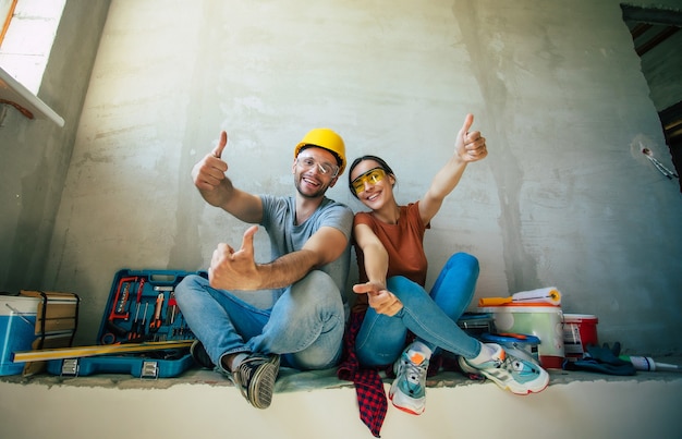 Foto modernes glückliches junges paar verliebt in freizeitkleidung während der reparatur oder renovierung von wänden mit vielen werkzeugen dafür