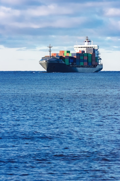 Modernes graues Containerschiff, das in stillem Wasser bewegt