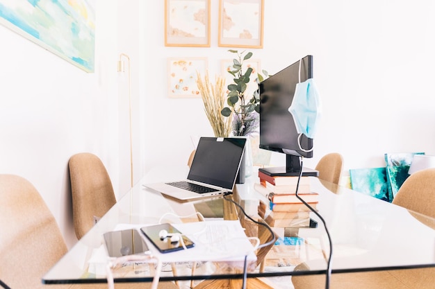 Modernes Heimbüro mit Gadgets und medizinischer Maske