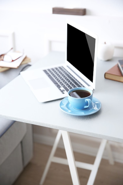 Modernes interieur. bequemer arbeitsplatz. tisch mit laptop und tasse kaffee, nahaufnahme