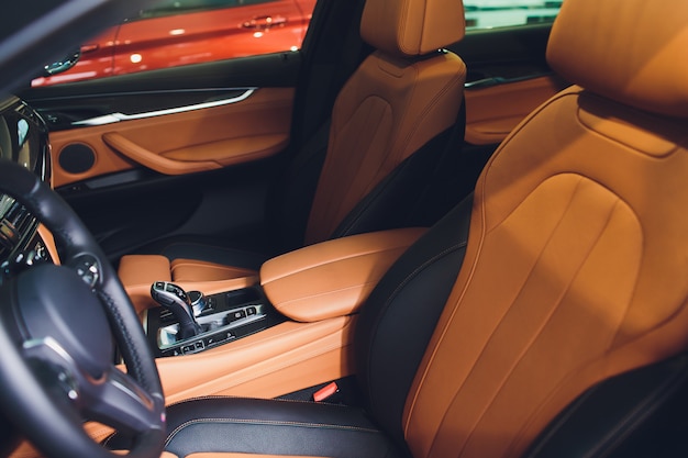 Modernes Luxusauto innen. Innenraum des Prestige modernen Autos. Bequeme braune Ledersitze. Orange perforiertes Ledercockpit.