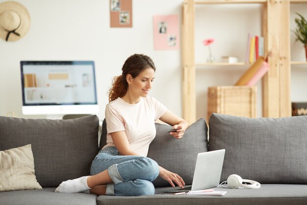 Modernes Mädchen, das Waren im Online-Shop kauft