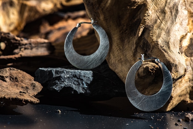 Modernes metallohr schellt auf wurzel und schwarzem steinhintergrund mit hartem lichteffekt