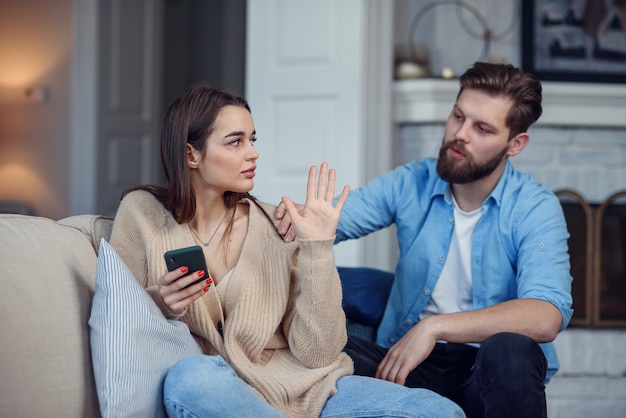 Modernes Paar zu Hause. Mann und Frau konzentrierten sich darauf, mit Smartphones zu kommunizieren, sich gegenseitig zu ignorieren und Zeit in sozialen Medien zu verbringen.