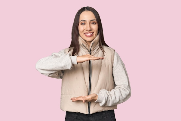 Modernes Porträt einer jungen kaukasischen Frau auf Studio-Hintergrund, die etwas mit beiden Händen hält