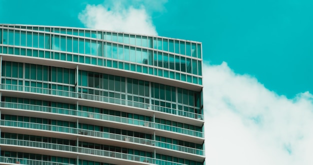 Moderno edificio de cristal de gran altura bajo un cielo azul con nubes esponjosas