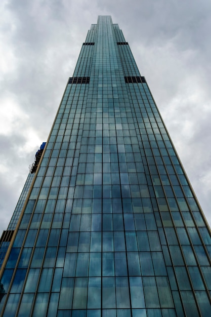 Moderno edificio de rascacielos de cristal frente al oscuro cielo nublado y tormentoso en vista en perspectiva