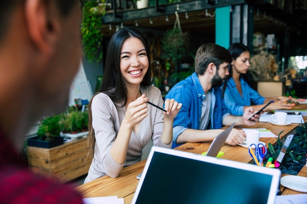 El moderno equipo de puesta en marcha feliz con ropa informal en la oficina o en el espacio de trabajo conjunto está trabajando y discutiendo sus planes e ideas