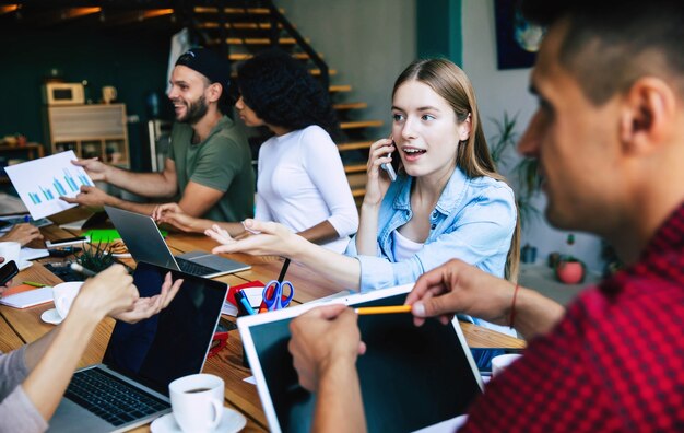 El moderno equipo de puesta en marcha feliz con ropa informal en la oficina o en el espacio de trabajo conjunto está trabajando y discutiendo sus planes e ideas