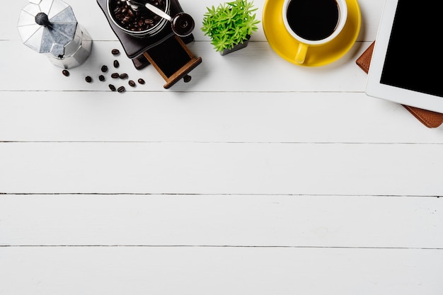 Moderno escritorio de madera blanca con cuaderno, lápiz, panadería, tableta y taza de café
