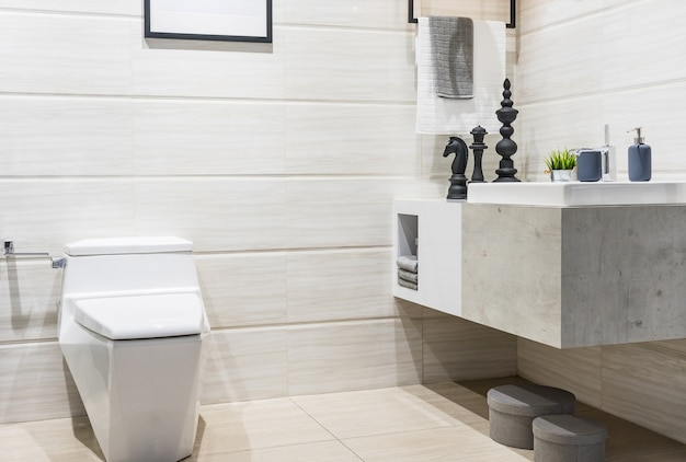Moderno y espacioso baño con azulejos brillantes con ducha de vidrio, inodoro y lavabo.
