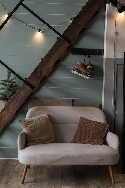 Moderno estilo hygge escandinavo estilo home sala de estar design de interiores Confortável sofá aconchegante com almofadas guirlanda brilhante luzes escadas parede azul Decorações de celebração de ano novo de natal elegante