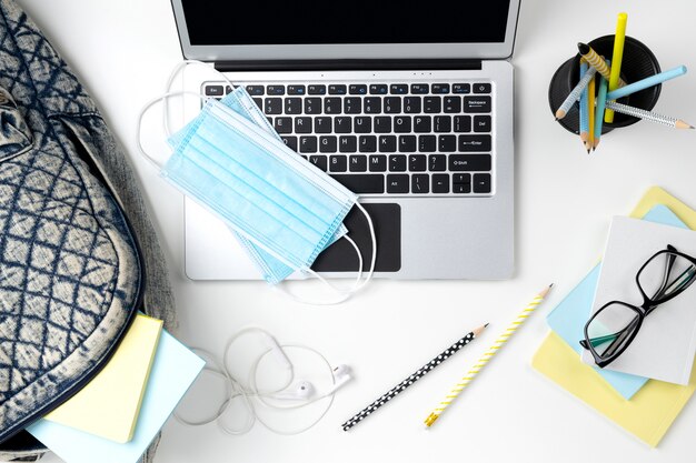 Moderno laptop com mochila e artigos de papelaria na mesa branca