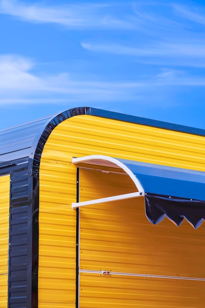 Moderno quiosco callejero de café de acero corrugado amarillo y negro con fondo de cielo azul