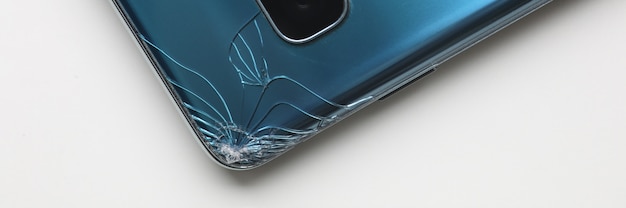 Foto moderno teléfono inteligente acostado a la mesa con crack en la esquina