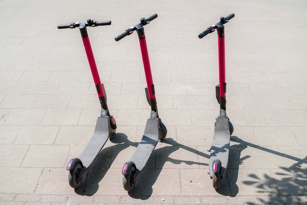 Foto modernos scooters eco eléctricos urbanos para alquilar al aire libre en la acera.