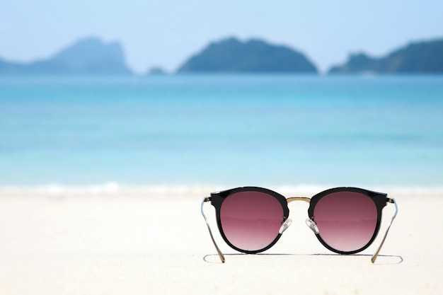 Modesonnenbrille auf Seestrand unter klarem blauem Himmel. Sommerferien entspannen sich Hintergrund mit Kopie spac