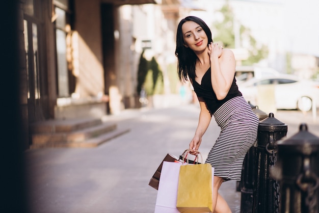 Modisch gekleidete Frau mit farbigen Einkaufstüten auf den Straßen, Einkaufskonzept