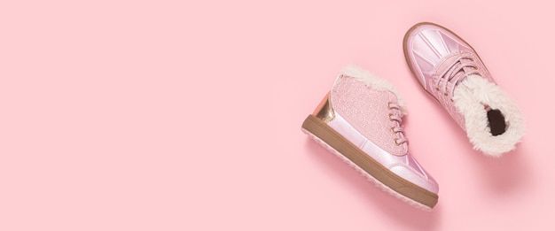 Modische Babyschuhe auf rosa Hintergrund. Ansicht von oben, flach. Banner.