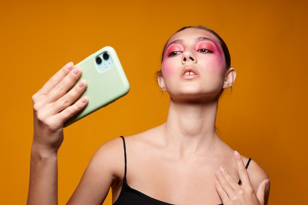 Modische Frau schaut auf das helle Make-up des Telefons, das Modegefühle aufwirft, isolierter Hintergrund unverändert