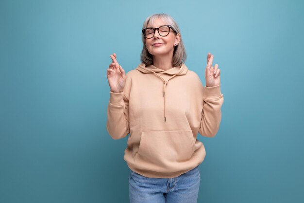 Modische Großmutter in einem Jugendoutfit auf Studiohintergrund mit Kopierraum