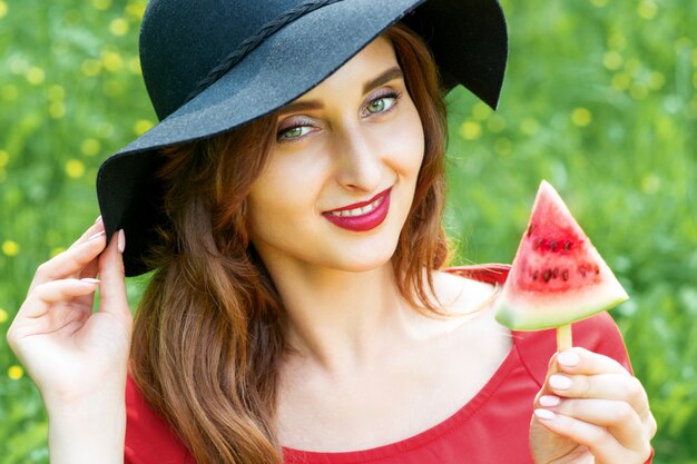 Modische junge Frau hält eine Scheibe Wassermelone.