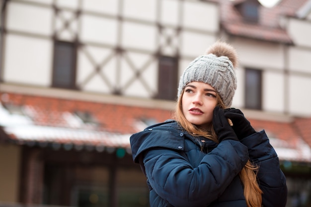 Modische rothaarige junge Frau mit trendigem Outfit posiert auf der Straße in Kiew