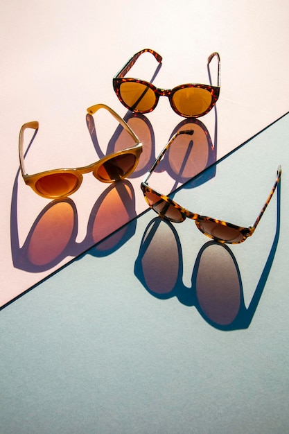 Modische Sommersonnenbrille mit langem Schatten auf rosa und blauem Hintergrund