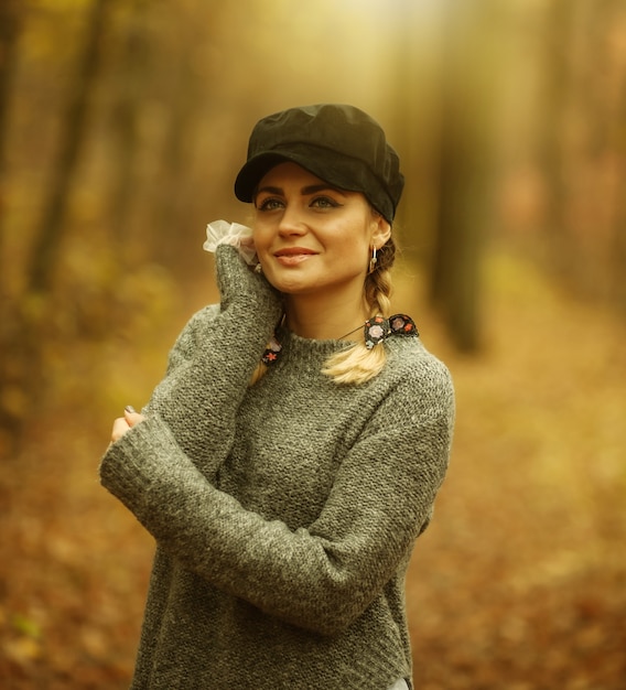 Modische stilvolle Frau mit Zöpfen in einer trendigen Mütze im Herbstwald