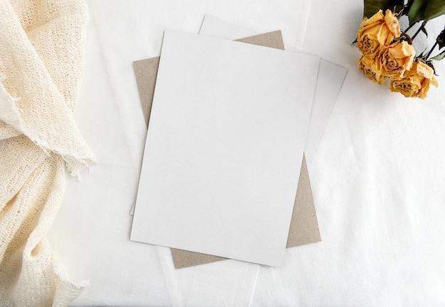 Modische Stock Briefpapier Hintergrund weiße Karte für Beschriftung und trockene gelbe Rosen auf einem weißen Tisch Hochzeit femininen Hintergrund Blank für eine Einladungskarte