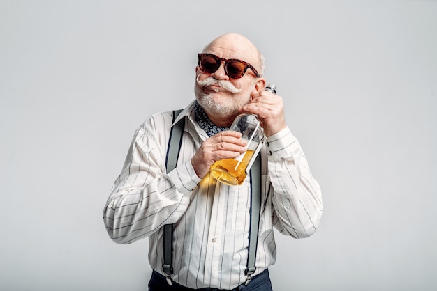 Modischer älterer Mann umarmt die Flasche guten Alkohols. Älterer Senior, Alter