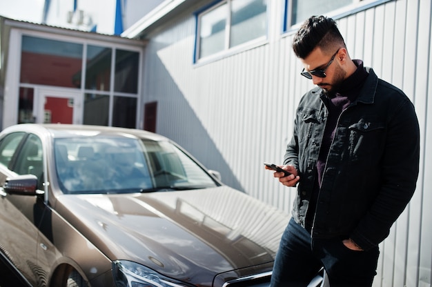 Modischer beearded junger Mann, der draußen mit großem Auto aufwirft