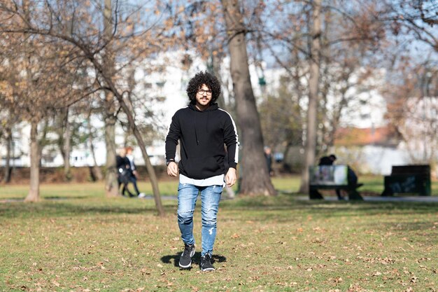 Modischer, gutaussehender Mann, der allein im Herbstpark posiert