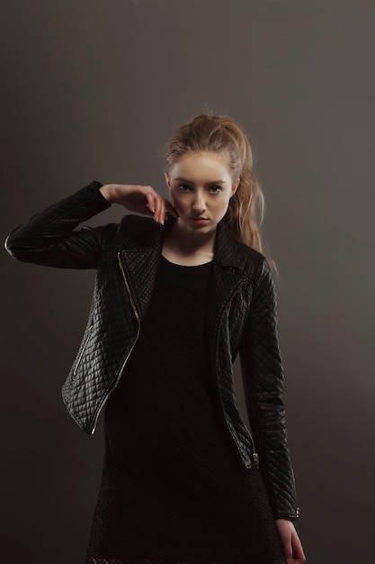 Modisches blondes Model posiert für Modeltests in schwarzer Jacke im Studio