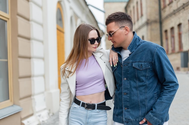 Modisches junges schönes Hipster-Paar mit Sonnenbrille in stylischer Frühlings-Denim-Kleidung geht in der Stadt spazieren