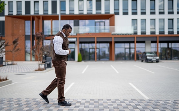 Modisches männliches Modell im Anzug, das auf der Straße geht Stilvoller gutaussehender Mann, der im Freien geht