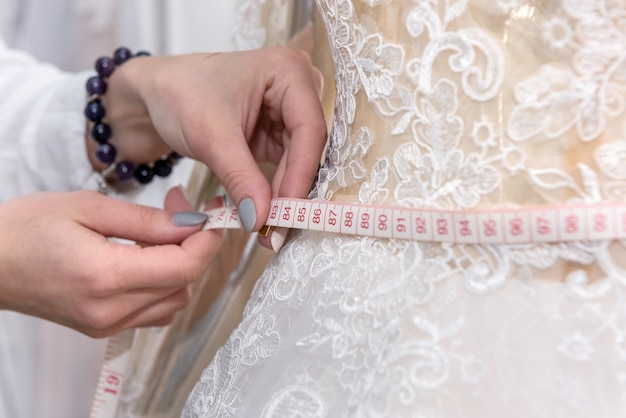 Modista midiendo la cintura del vestido en maniquí