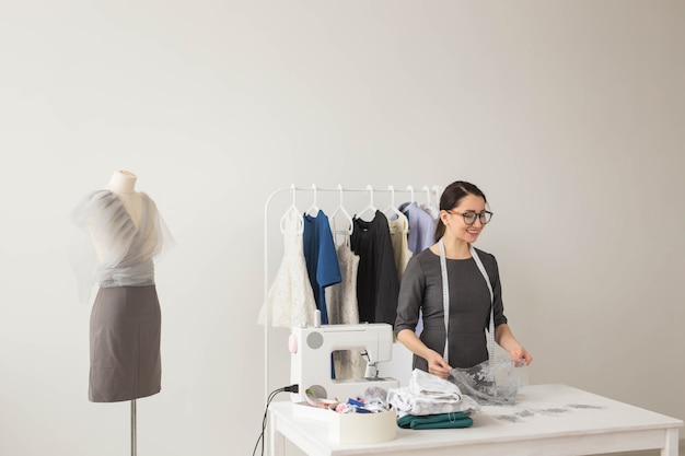 Modista, tecnología, diseñadora de moda y concepto de sastre: joven diseñadora de moda que trabaja en su sala de exposición.