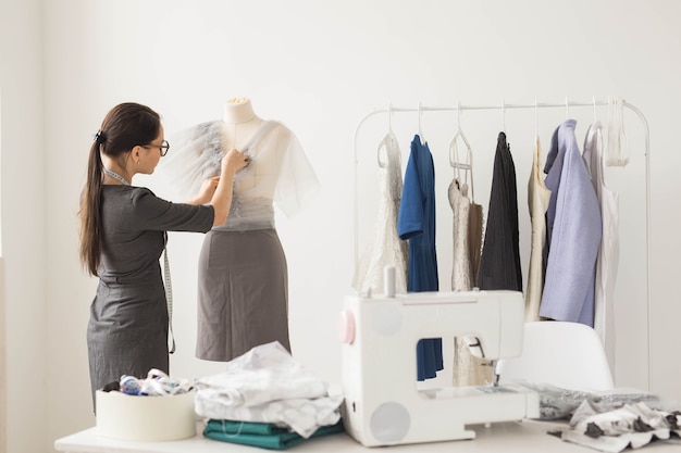 Modista, tecnologías, diseñadora de moda y concepto de sastre: joven diseñadora de moda que trabaja en su sala de exposición